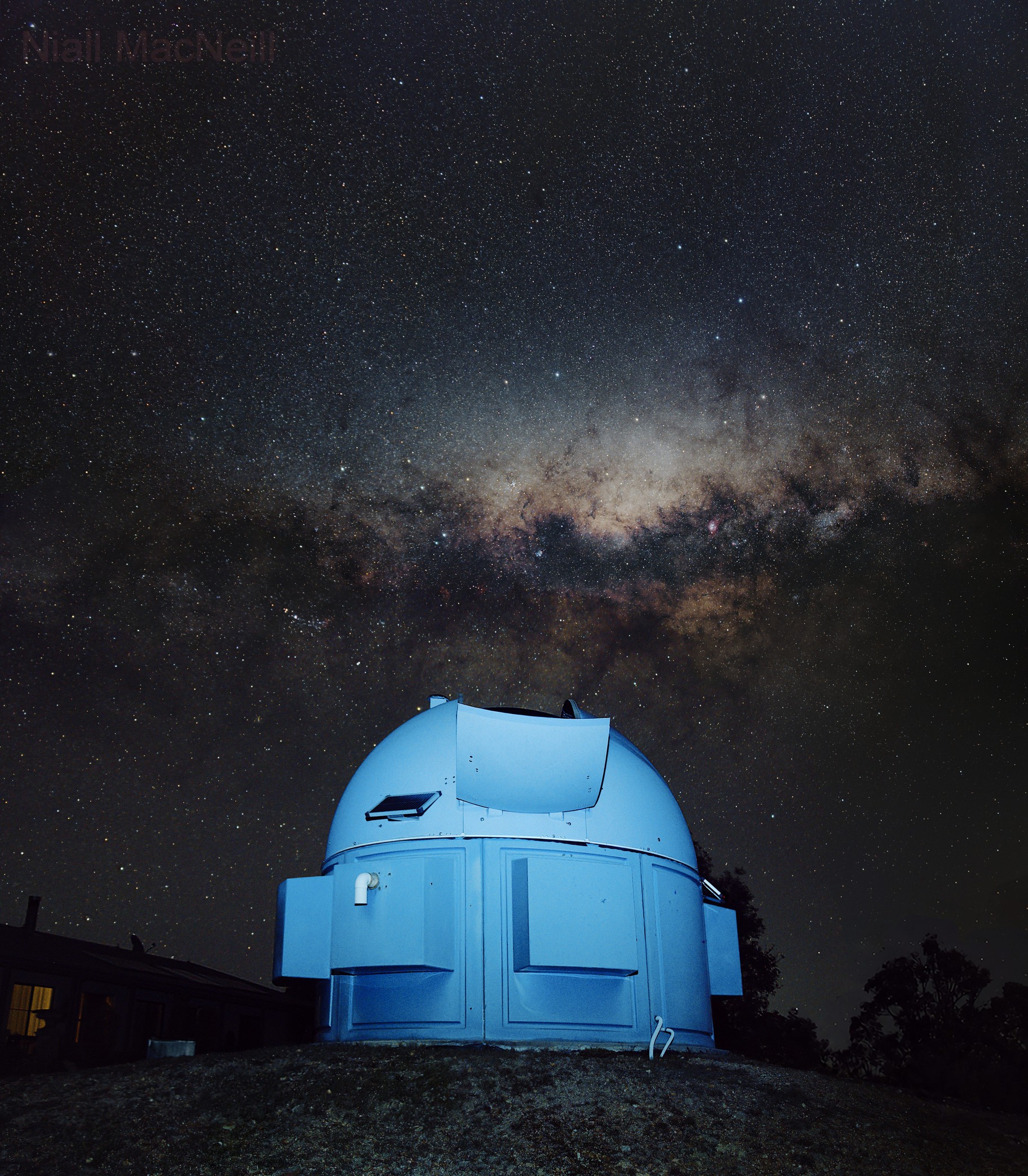 The Central Core of the Milky Way Galaxy low in the western sky over a domed observatory